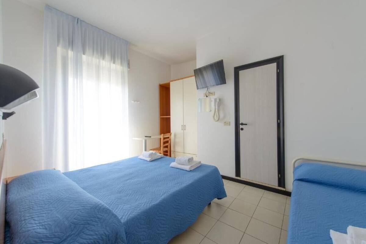 A hotel room with two beds, a TV, a telephone, and a wardrobe.