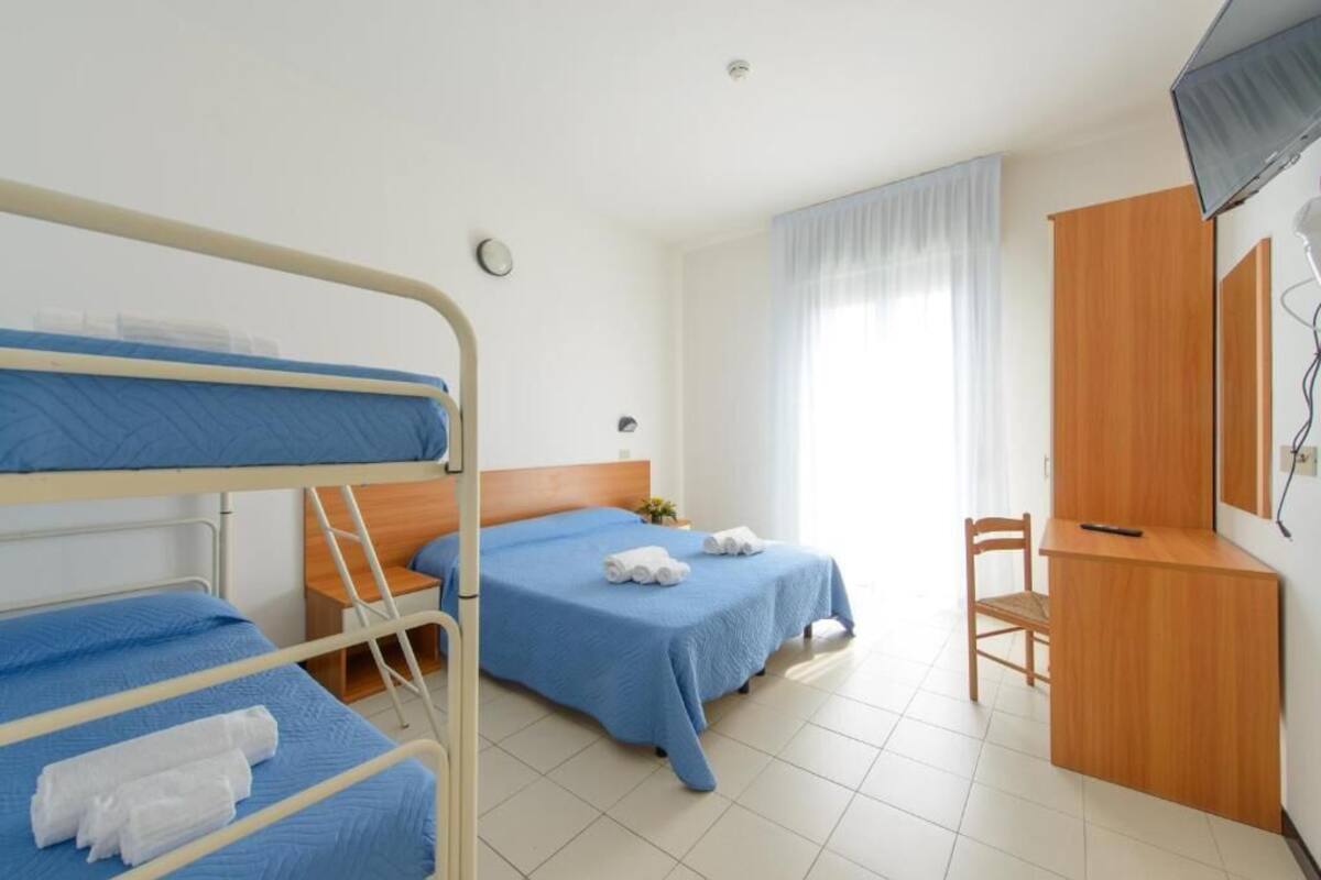 A hotel room with bunk beds, a desk, a chair, and a TV.
