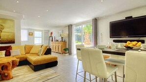 A spacious living room with a sofa, dining area, and a TV. - Beautiful semi-detached villa of 115 m2, cosy and quiet. (calenzana)