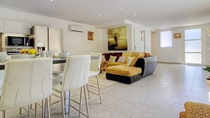 A modern living room with a sofa, a dining area with chairs, and a kitchen area with a microwave. - Beautiful semi-detached villa of 115 m2, cosy and quiet. (calenzana)