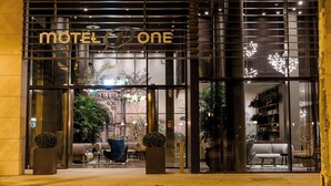 L’extérieur d’un motel au design moderne, avec une enseigne bien visible, de grandes portes vitrées et un intérieur bien éclairé, que l’on peut apercevoir à travers les fenêtres.