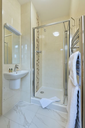 A modern bathroom with a glass-enclosed shower, a sink with a mirror, and a towel rack. - The Bocardo Hotel (Oxford)