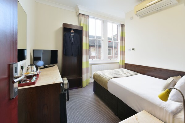 A hotel room with a bed, a desk with a TV, a wardrobe, and a window with curtains. - The Bocardo Hotel (Oxford)