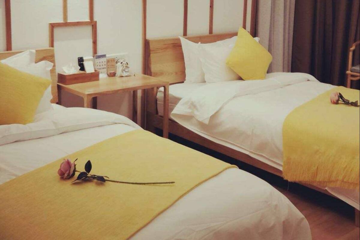 A hotel room with two beds, wooden headboards, and a small table with toiletries.