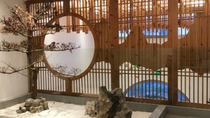 Una habitació japonesa tradicional amb una porta corredissa de fusta, un arbre petit i un jardí de pedres.