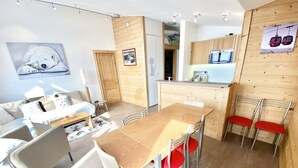 Una sala de estar moderna con una mesa de comedor de madera, sillas rojas, un sofá y un cuadro en la pared.