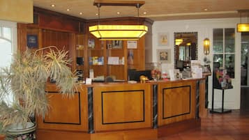 A reception desk with a wooden finish, a large potted plant, and a sign above the desk.