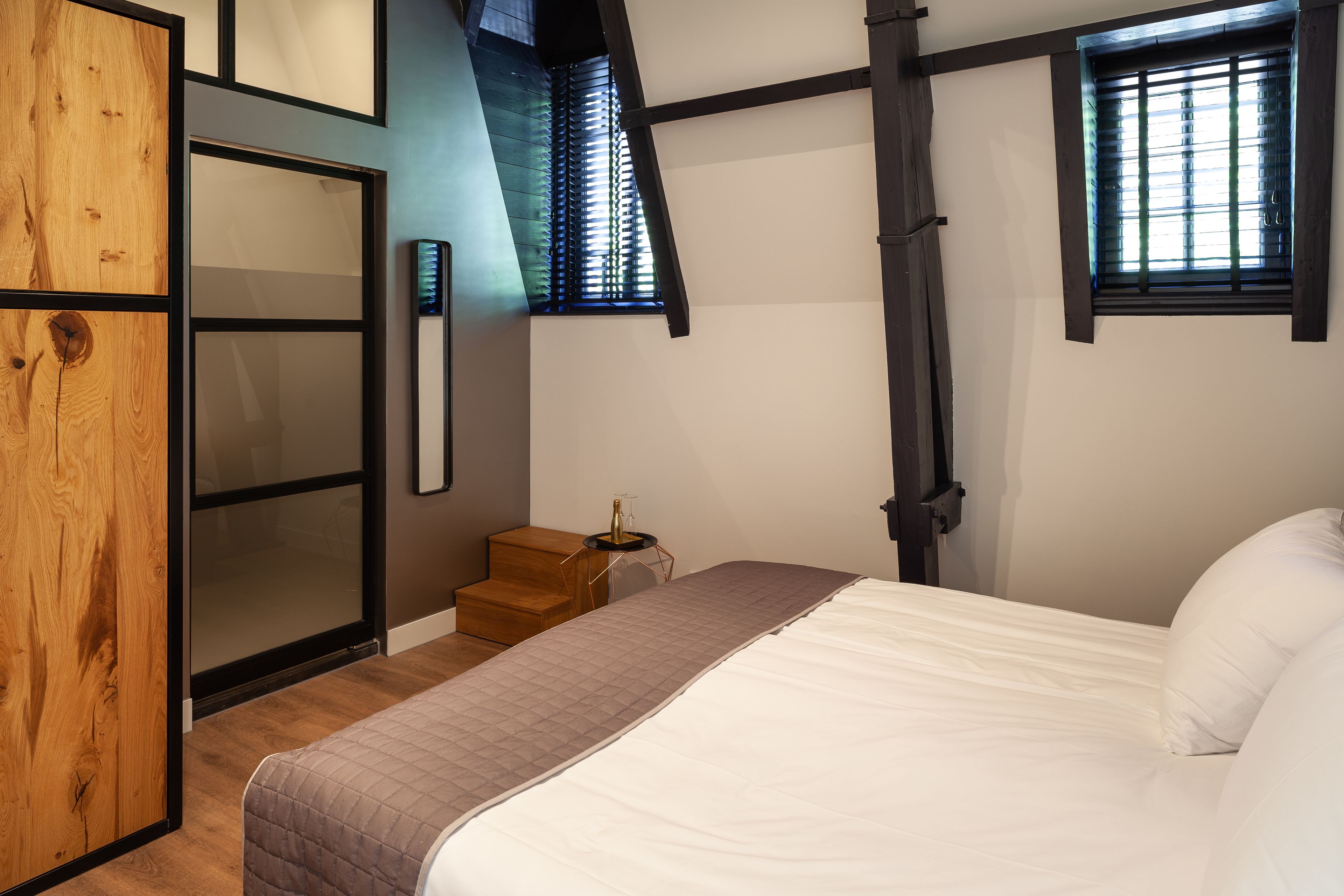 Quarto com cama, guarda-roupa de madeira e janela com persianas.