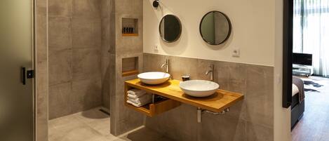 A modern bathroom with a walk-in shower, two sinks, and a vanity with storage.