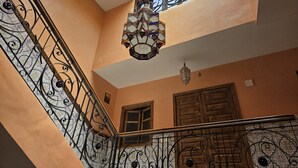 A staircase with ornate metal railings, a stained glass light fixture, and wooden doors. - Riad Jasmeene: Exclusive rental with WiFi and access to Pools!  (Marrakech)