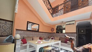 A room with a checkered floor, a white dining table, a sofa, and a decorative wall. - Riad Jasmeene: Exclusive rental with WiFi and access to Pools!  (Marrakech)