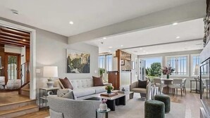 A modern living room with a sofa, coffee table, ottoman, and dining area with chairs.