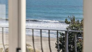 A view of the ocean through a window with a metal railing.