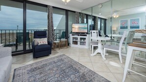 Un salon moderne avec un balcon, une télévision et un coin repas.