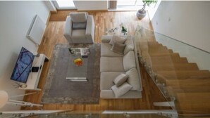A modern living room with a sofa, coffee table, and a staircase. - Tailored Stays  -  Executive Town House (Cambridge)