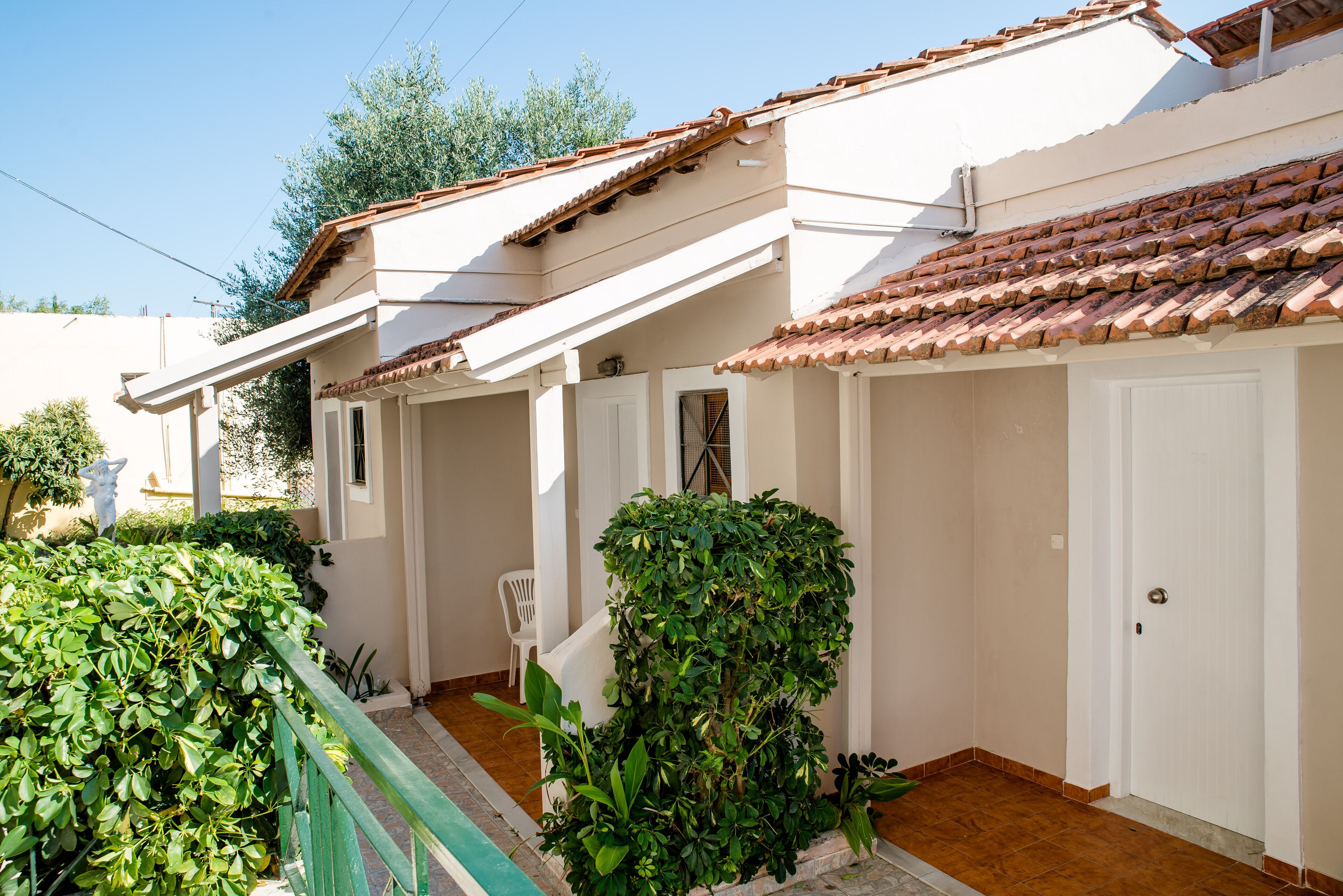 A white building with a tiled roof, a covered porch, and a door.