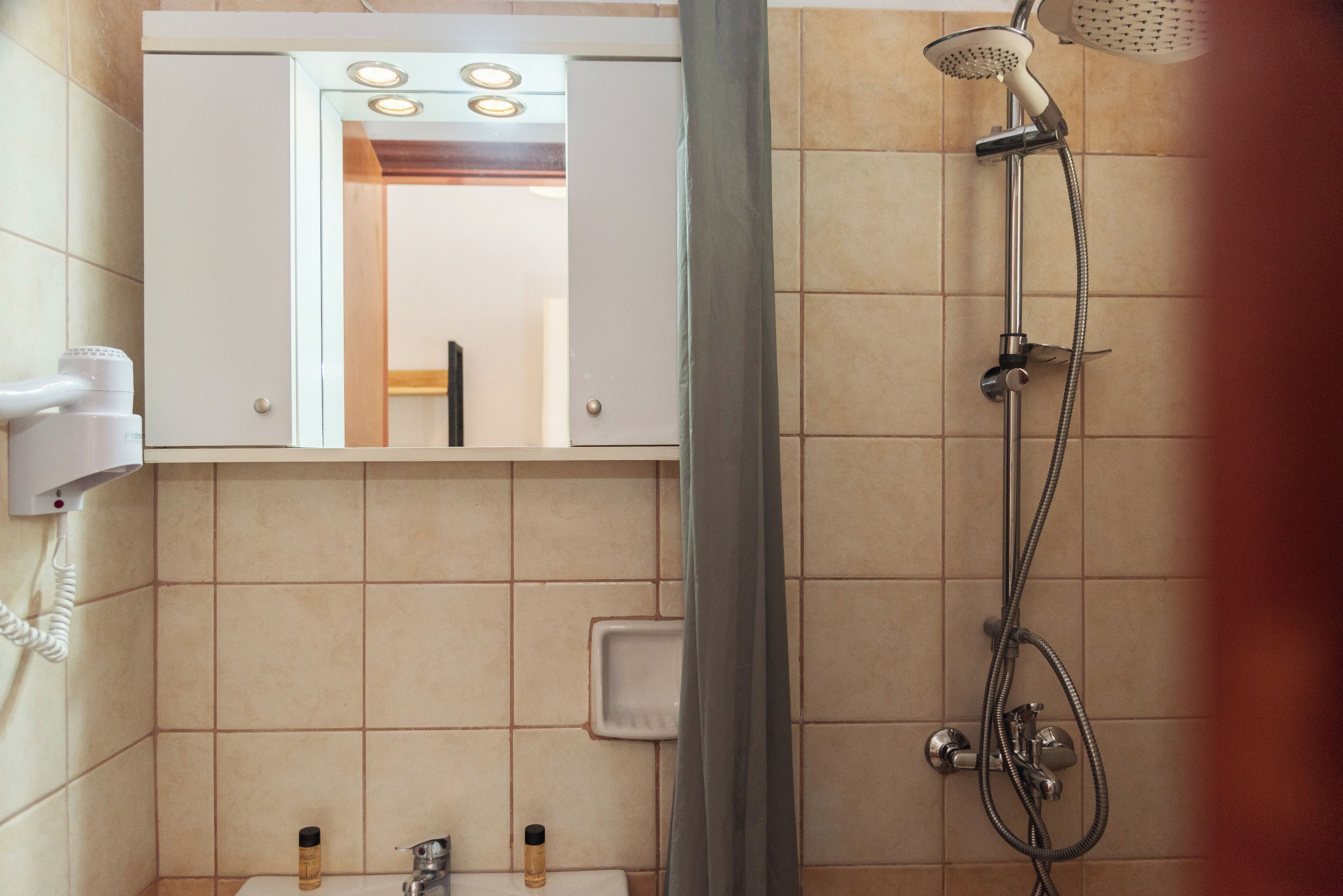 A bathroom with a shower, a mirror, and a hairdryer.