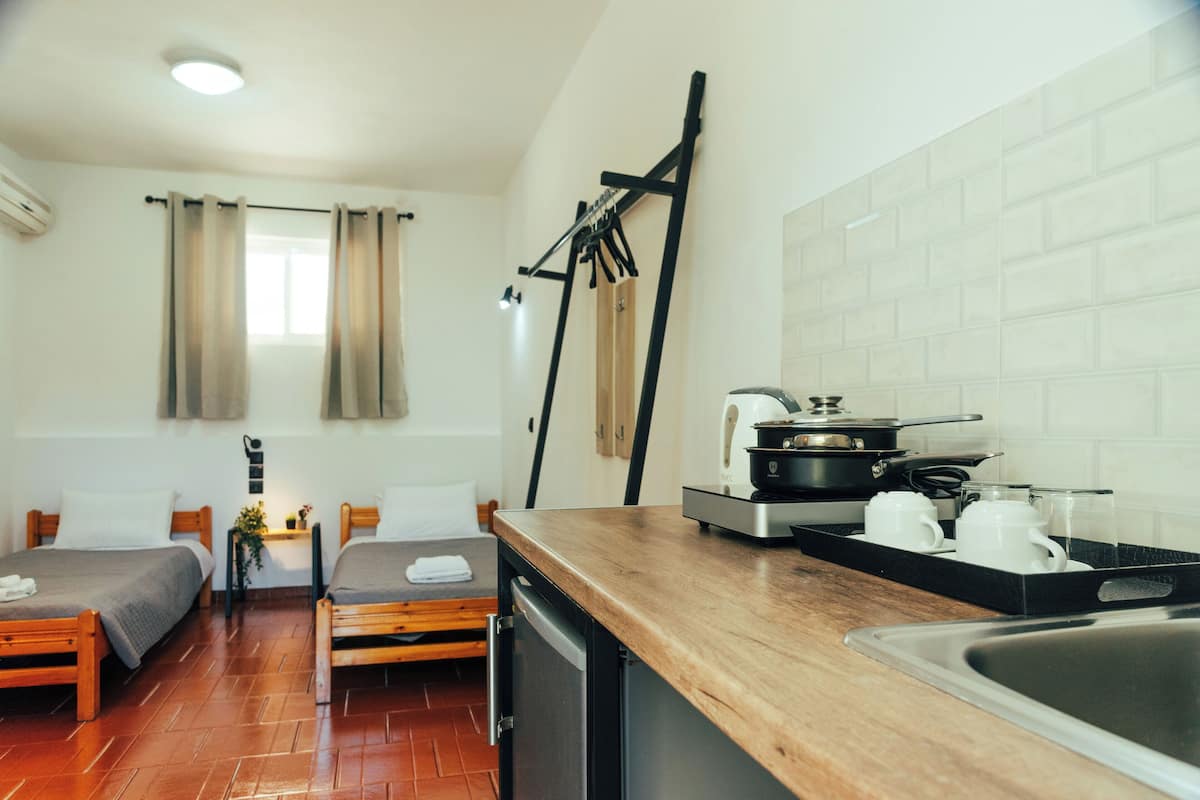 Una habitación compacta con kitchenette, una cama y una pequeña mesa.