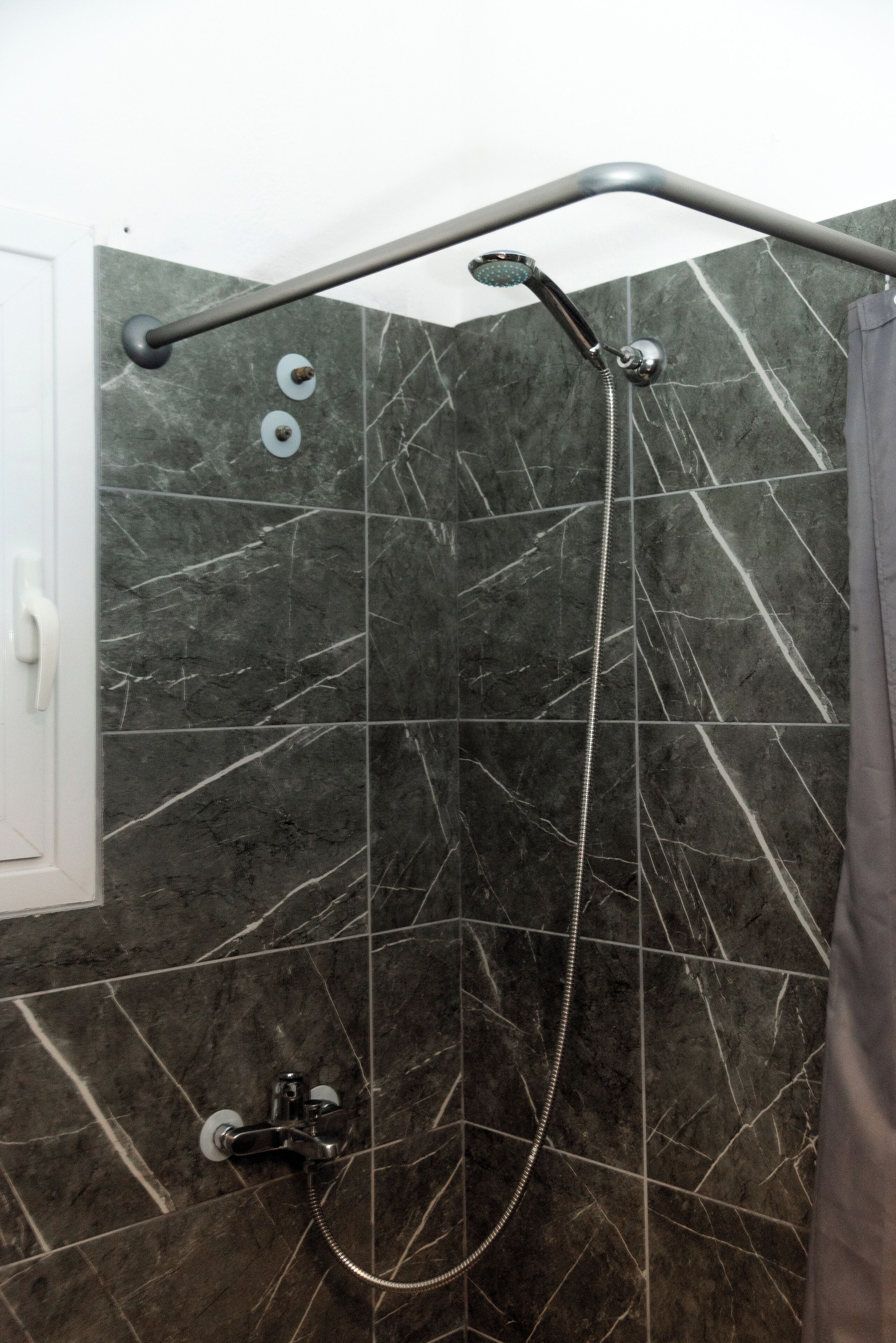 A shower with a handheld showerhead and a handheld faucet.