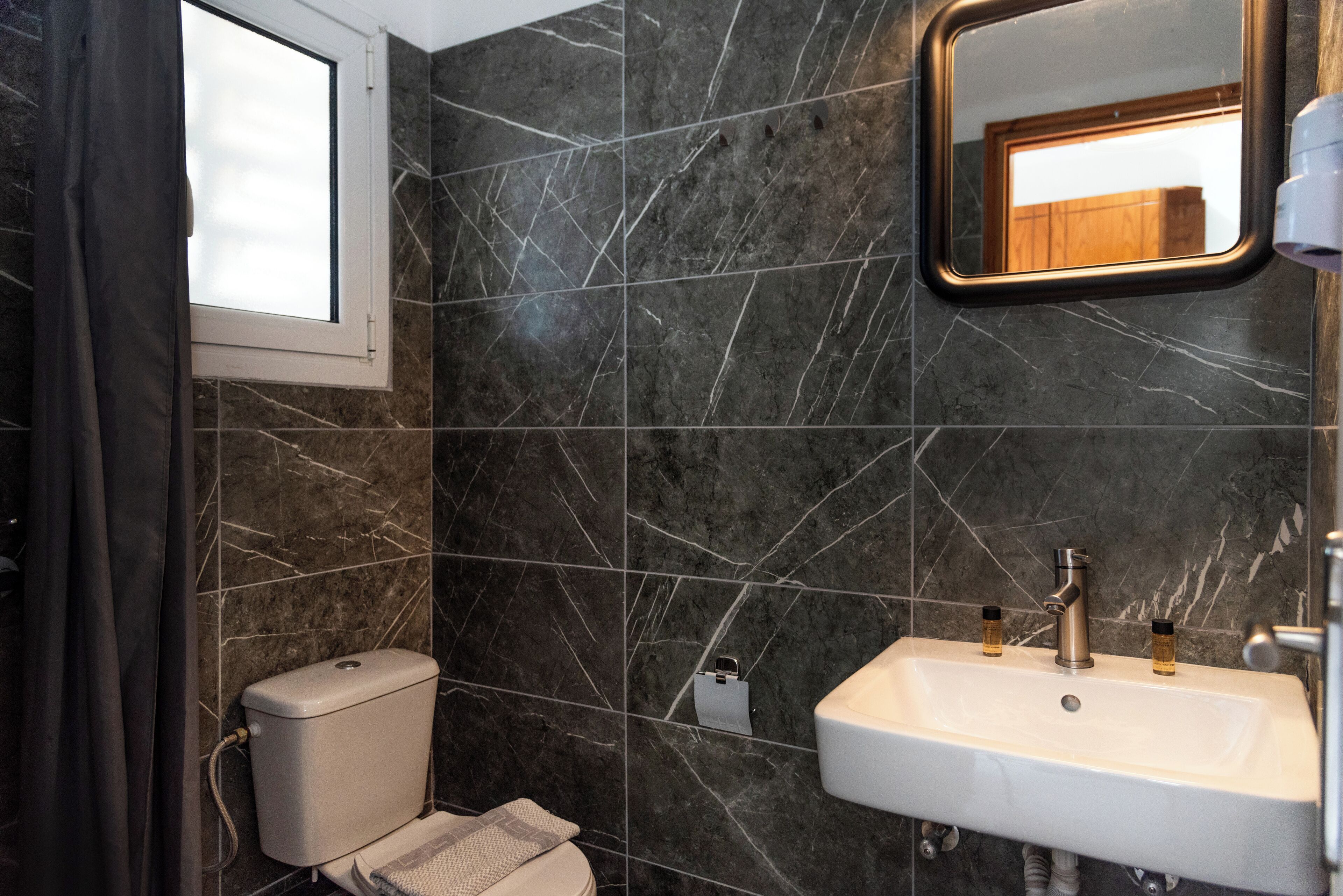Un baño con inodoro, lavabo y espejo.