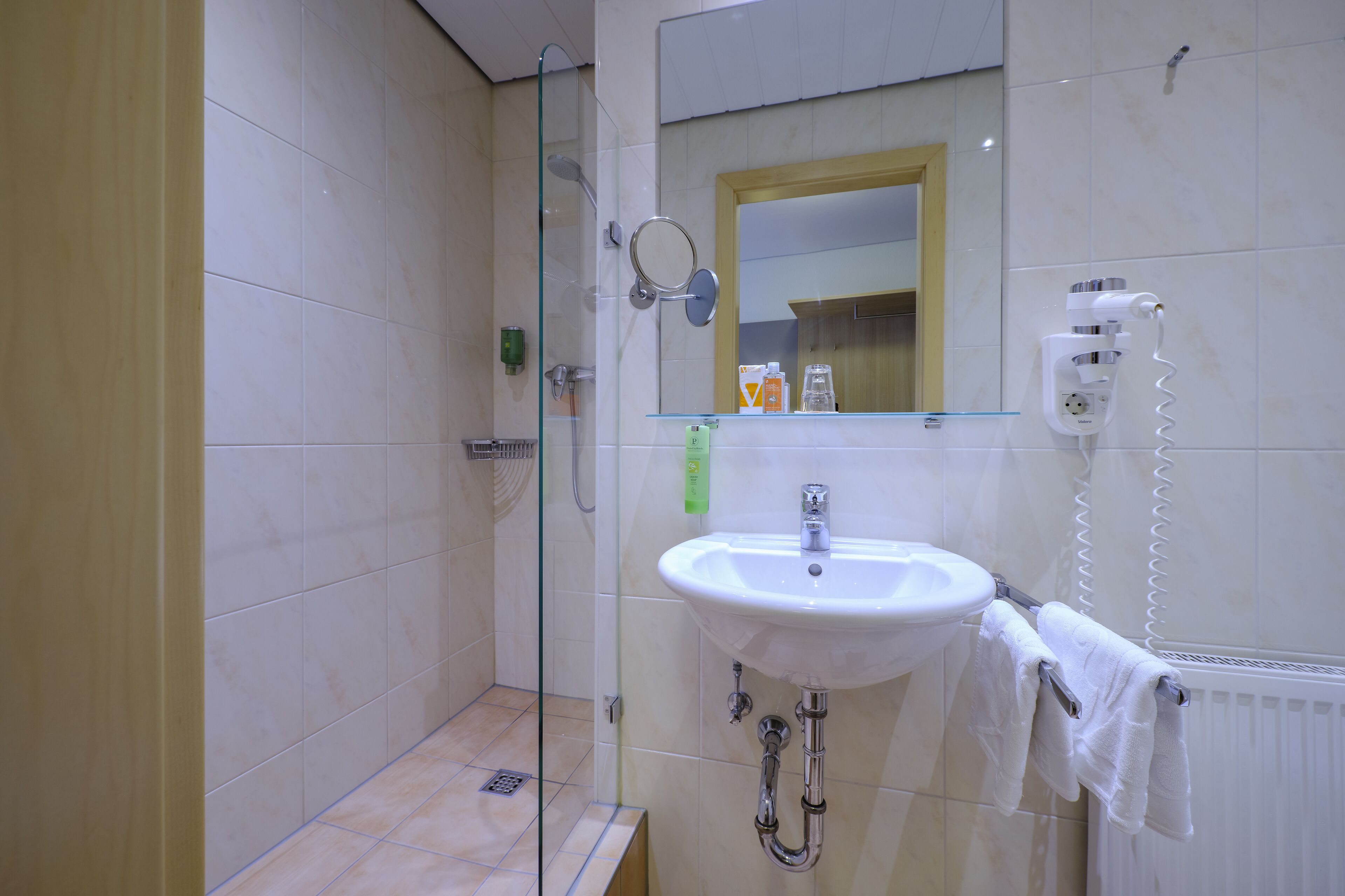 A bathroom with a glass shower enclosure, a sink with a towel rack, and a mirror above the sink.