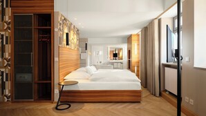 A modern hotel room with a large bed, a walk-in closet, a bathroom with a mirror and sink, and a TV. - Hotel Victoria (Nuremberg)