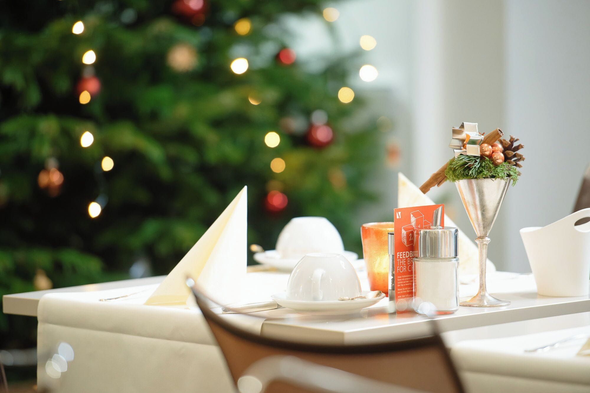 Una mesa de comedor preparada con una vela, un vaso de agua y un centro de mesa decorativo.