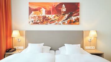 Ein Hotelzimmer mit zwei Betten, einem Bild an der Wand und zwei Nachttischlampen.