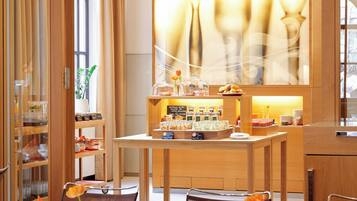 A modern hotel lobby with a wooden reception desk, a glass display case, and a seating area with chairs and tables.