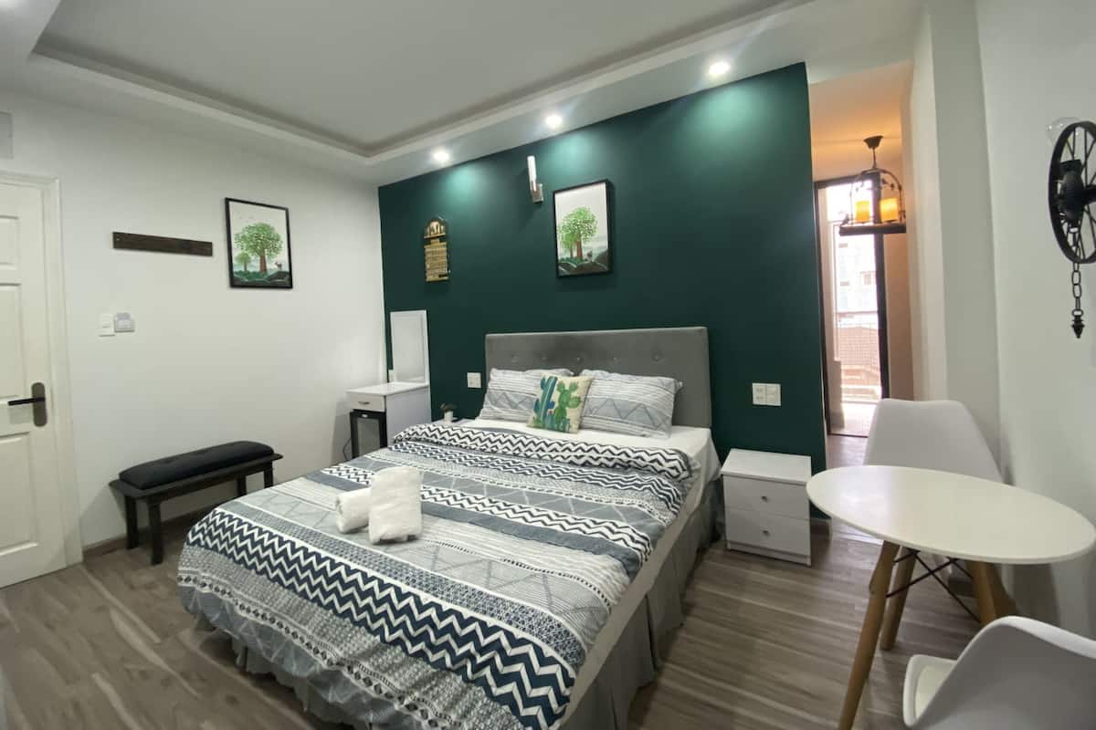 Um quarto moderno com cama, mesas de cabeceira, um banco, uma cadeira e uma pequena mesa.