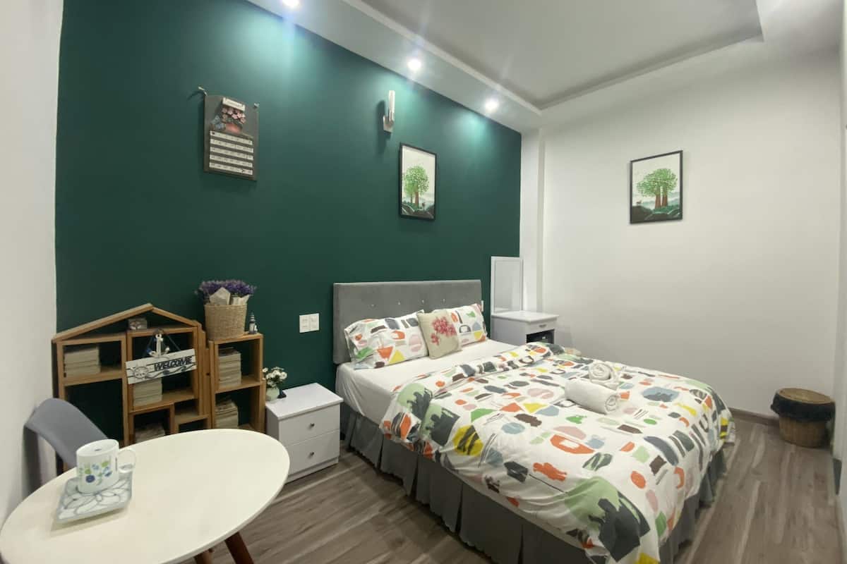 Quarto moderno com cama, mesa de cabeceira e pequena escrivaninha com cadeira.