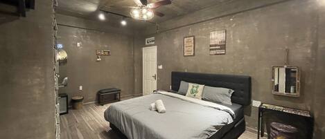 Un dormitorio con cama, ventilador de techo, banco y puerta.