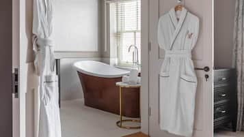 A modern bathroom with a freestanding bathtub, a towel rack, and a robe hanging on a door.
