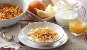 Desayuno con cereal, fruta, leche y zumo de naranja.