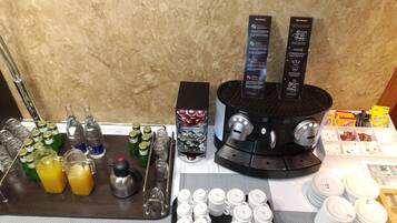 A bar area with a coffee machine, bottles, glasses, and a tray with utensils.