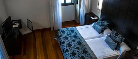 A hotel room with a bed, a desk, and a chair.