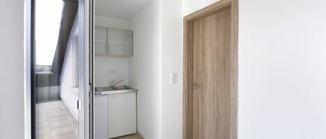 Una cocina moderna con un lavamanos y armarios, una puerta de madera y un ventanal que da a un balcón.