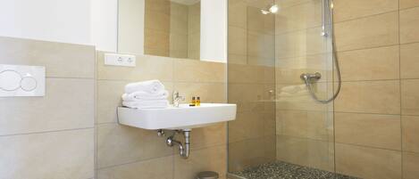 A modern bathroom with a glass-enclosed shower, a white sink, and a toilet.