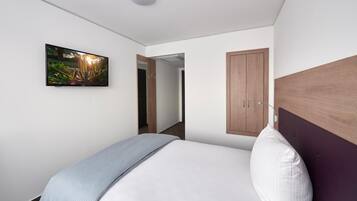 Un dormitorio moderno con una cama, un televisor montado en la pared y un armario de madera.
