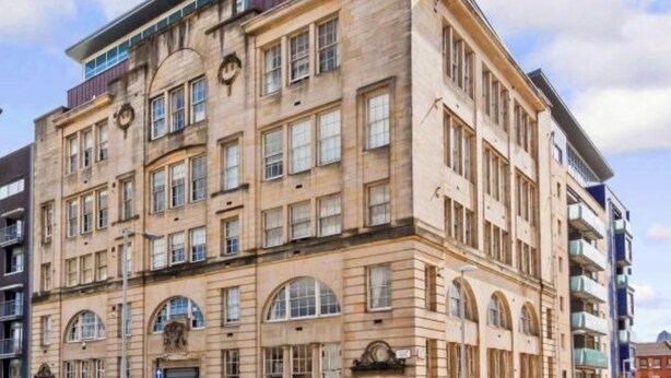 Un edificio de varios pisos con estilo arquitectónico clásico, que presenta ventanas arqueadas y una fachada simétrica.