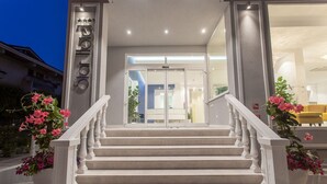 Entrada de hotel con una escalera, un puerta de vidrio y una silla amarilla en el exterior.