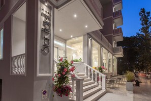 A hotel entrance with a staircase, a sign reading "Star Hotel," and outdoor seating area. - Hotel Star (Cesenatico)