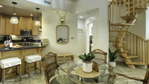Una cocina moderna con armarios de madera, microondas integrado y una mesa de comedor de vidrio con sillas.