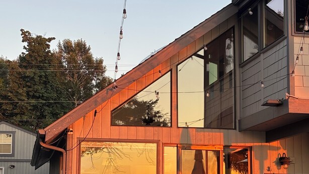 Una casa moderna con terraza, ventanas amplias y mobiliario exterior.