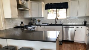 Una cocina moderna con armarios blancos, encimera negra, electrodomésticos de acero inoxidable y una ventana con unísimo.
