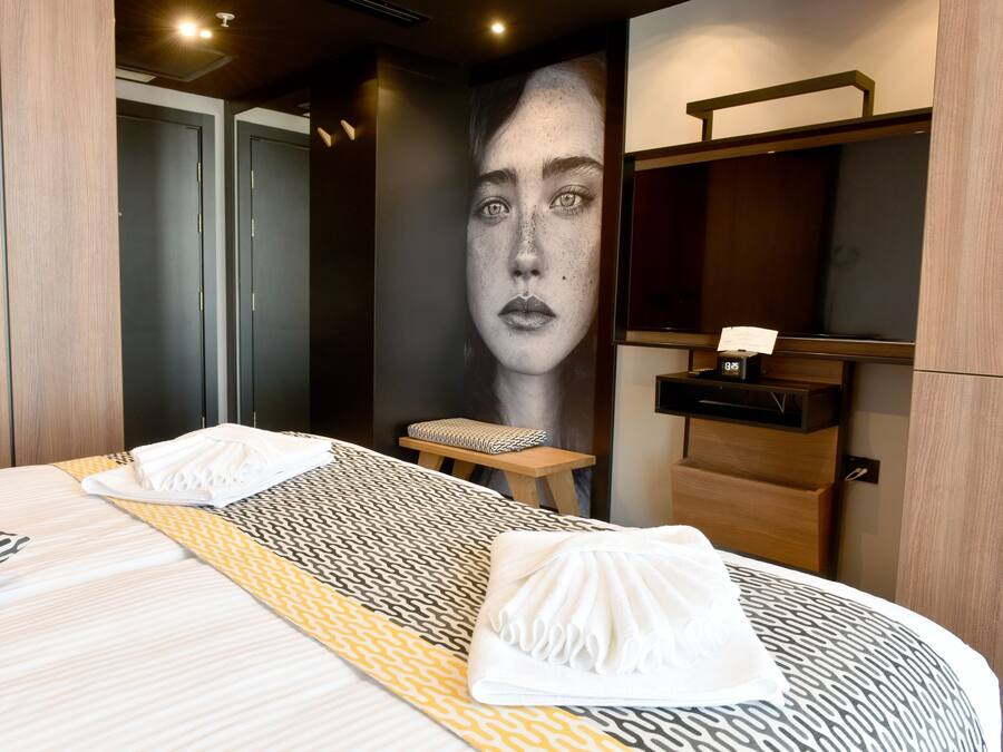 Una camera d'albergo con un letto grande, un comodino, uno specchio e una parete con un ritratto.
