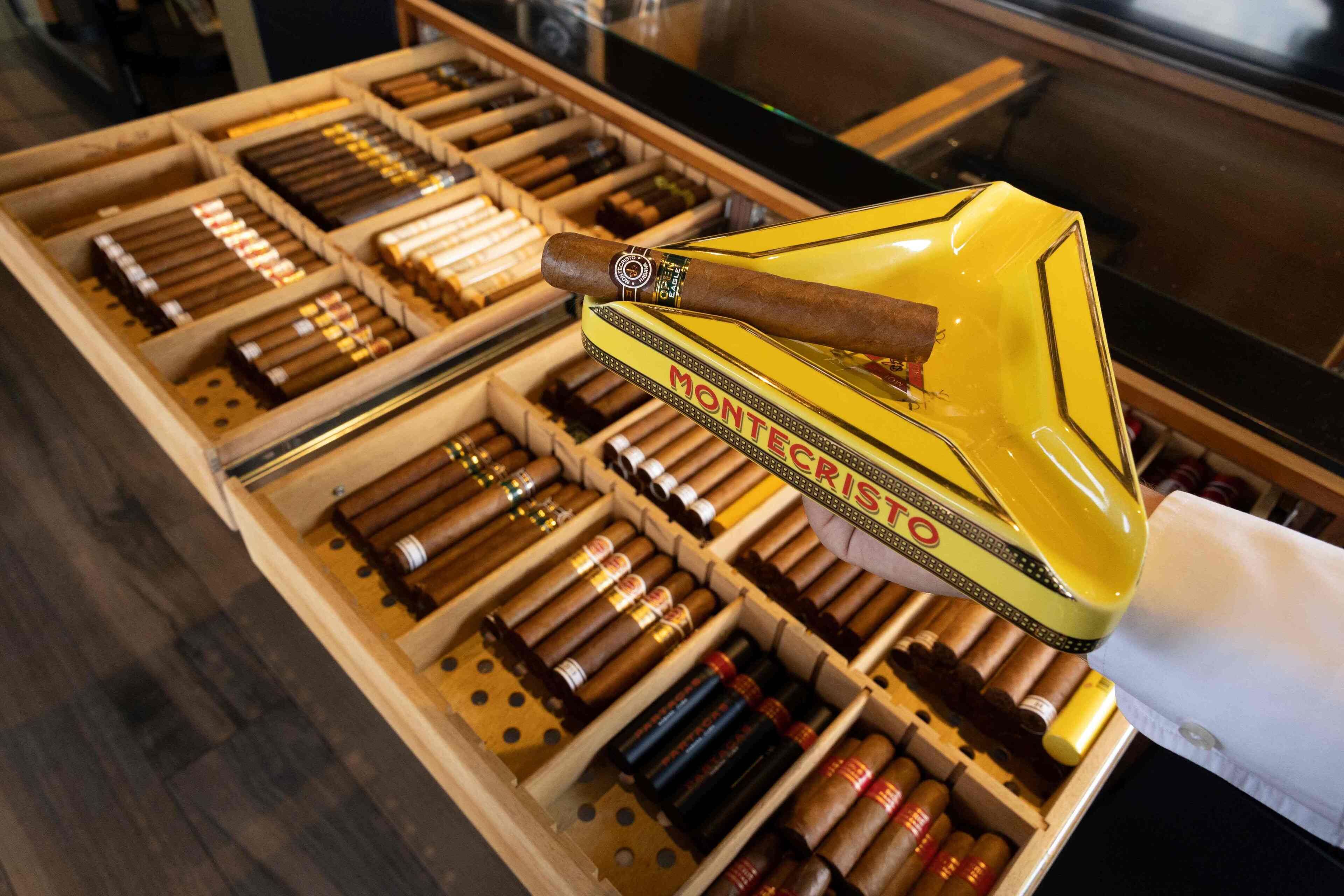 Una exhibición de cigarros en una caja de madera, con un estuche amarillo para cigarros encima.
