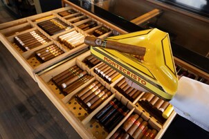 Una exhibición de cigarros en una caja de madera, con un estuche amarillo para cigarros encima.