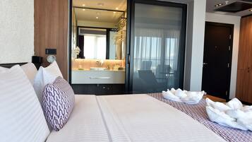 Habitación de hotel moderna con una cama grande, un baño con espejo y vistas a la ciudad.