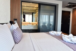 Habitación de hotel moderna con una cama grande, un baño con espejo y vistas a la ciudad.